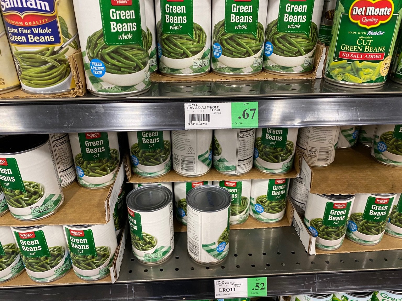 A picture of canned green beans on the shelf of a grocery store.